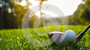 Golf ball and golf club in a beautiful golf course at sunset background