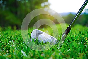 Golf ball and golf club in the beautiful golf course in Thailand. Collection of golf equipment resting on green grass with green