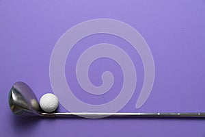Golf ball and golf club on purple background, sport concept