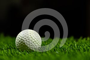 Golf ball on grass in black background