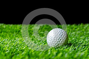 Golf ball on grass in black background