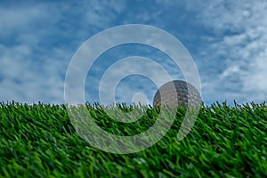 Golf ball on grass and blue sky background