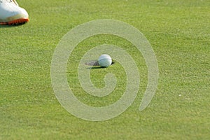 Golf ball on the grass with a few centimeters left to fall into the hole