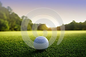 Golf ball on green in beautiful golf course at sunset background