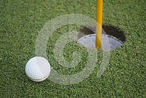 Golf ball on green grass in front of hole