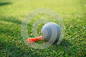 Golf ball on green grass sunset background