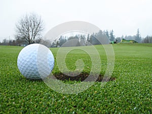 Golf ball beside hole