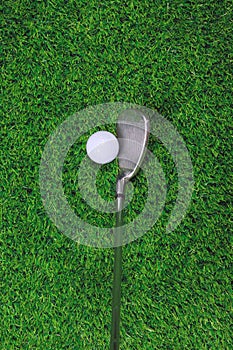 Golf ball and iron club on grass