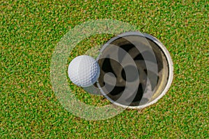 Golf ball on lip of cup at golf court