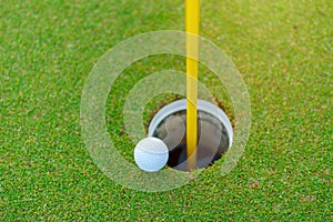 Golf ball on lip of cup at golf court