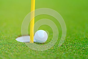 Golf ball on lip of cup at golf court