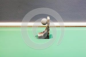 A golf ball with a marble base on top a glass green table as an abstract installation