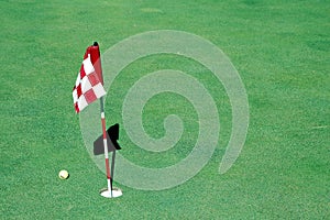 Golf ball near hole and flag