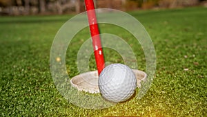 Golf ball near hole with flag