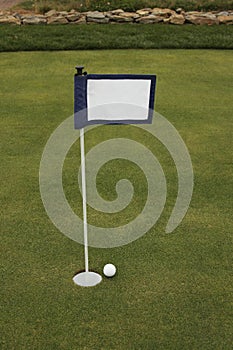 Golf ball near hole near putting green flag