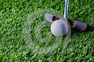 Golf ball with putter on green grass
