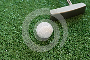 Golf ball and putter on green lawn background