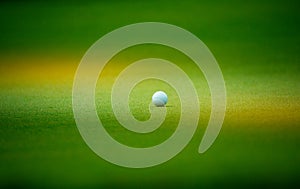 Golf ball putting on green grass near hole golf to win in game at golf course with blur background and sunlight ray