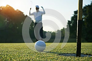 Golf ball putting on green grass near hole golf to win in game at golf course with sunset background