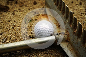 Golf ball and raking sand on bunker in beautiful golf course at