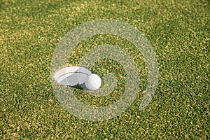 Golf ball sits at the lip of the hole on the putting green.