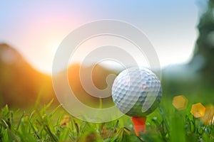 Golf ball on tee in beautiful golf course with sunset.