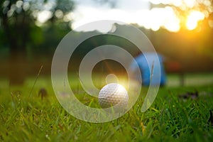 Golf ball on tee in beautiful golf course at sunset background