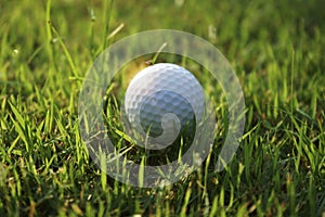 Golf ball on tee in beautiful golf course at Thailand. Collection of golf equipment resting on green grass with green background