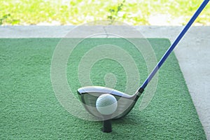 Golf ball on tee with driver club, in front of driver, driving r