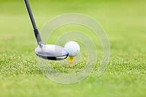 Golf ball on tee in front of driver