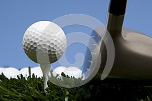 Golf ball on tee on grass with driver