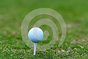 Golf ball on a tee with green background