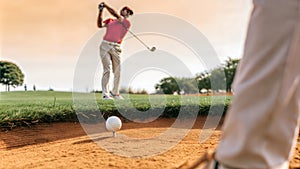 Golf ball on tee in a sand bunker