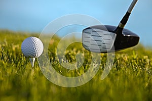 Golf ball about to be struck by driver with grass