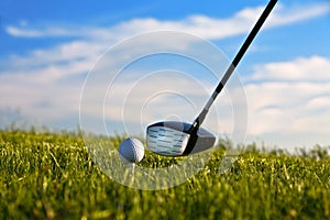 Golf ball about to be struck by driver with grass
