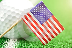 Golf ball with USA flag on green lawn or field.