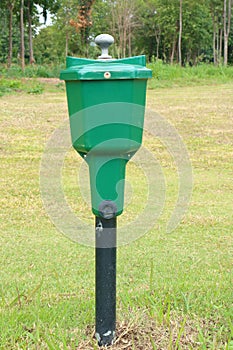 Golf ball washer with green golf course background.