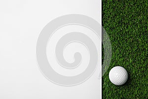 Golf ball and white paper on green artificial grass, space for text
