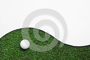 Golf ball and white paper on green artificial grass, top view