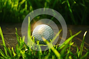 golf ball on wooden floor in beautiful golf course at sunset background