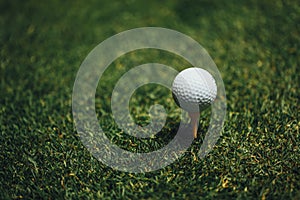 Golf ball on yellow tee on green grass