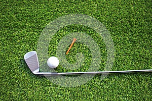 Golf balls and golf clubs on green grass