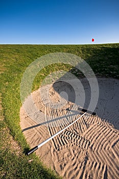 Golf bunker with rake and red flag