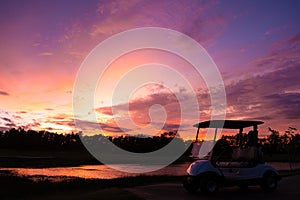 Golf cart car in fairway of golf course with fresh green grass field and cloud sky