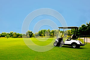 Golf cart car in fairway of golf course with fresh green grass field and cloud sky