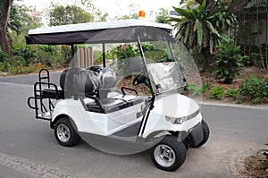 A golf cart car parked at a road in a garden golf course