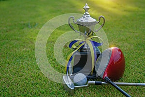 Golf champion trophy on green grass with golf clubs and golf ball in beautiful golf course