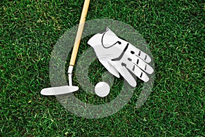 Golf club, ball and glove on green grass, flat