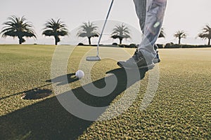 Golf club and ball in grass at the Golf course. White Golf ball on Green field golf course in morning time with sun light.