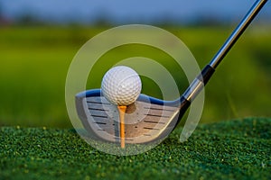 Golf club and ball on green grass ready to be struck on golf course background